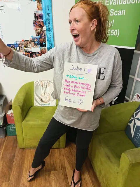 At the club, a smiling member shows the results written on her board