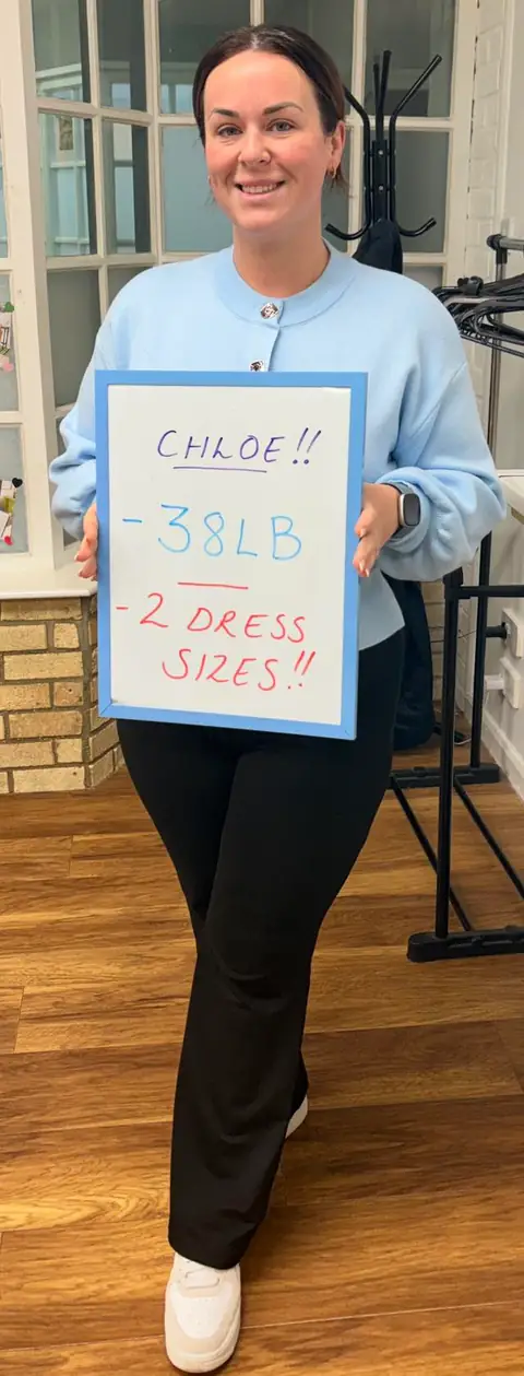 At the club, a smiling member shows the results written on her board